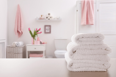 Image of Stack of fresh towels on light grey table in bathroom. Space for text