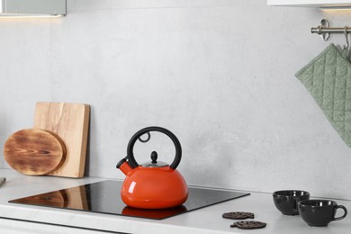 Photo of Red kettle with whistle on cooktop in kitchen