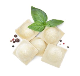 Uncooked ravioli, basil and peppercorns on white background, top view