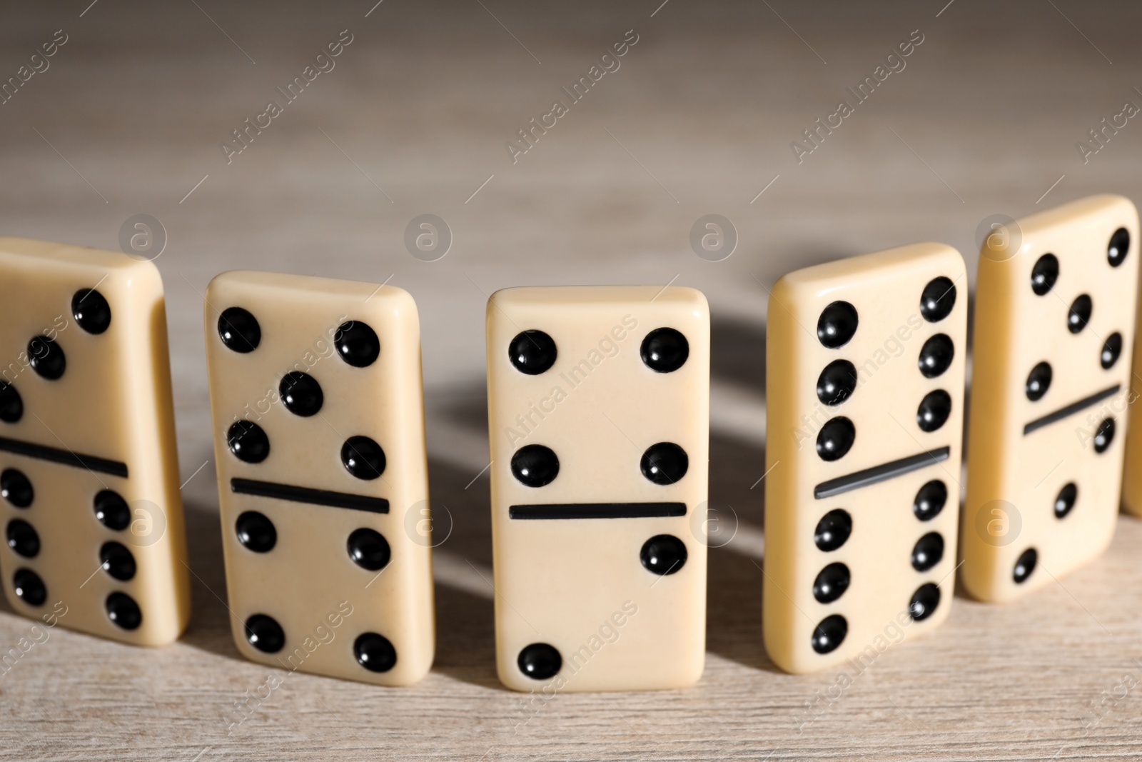 Photo of Classic domino tiles on wooden table, closeup