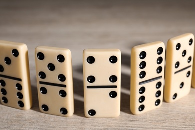 Photo of Classic domino tiles on wooden table, closeup