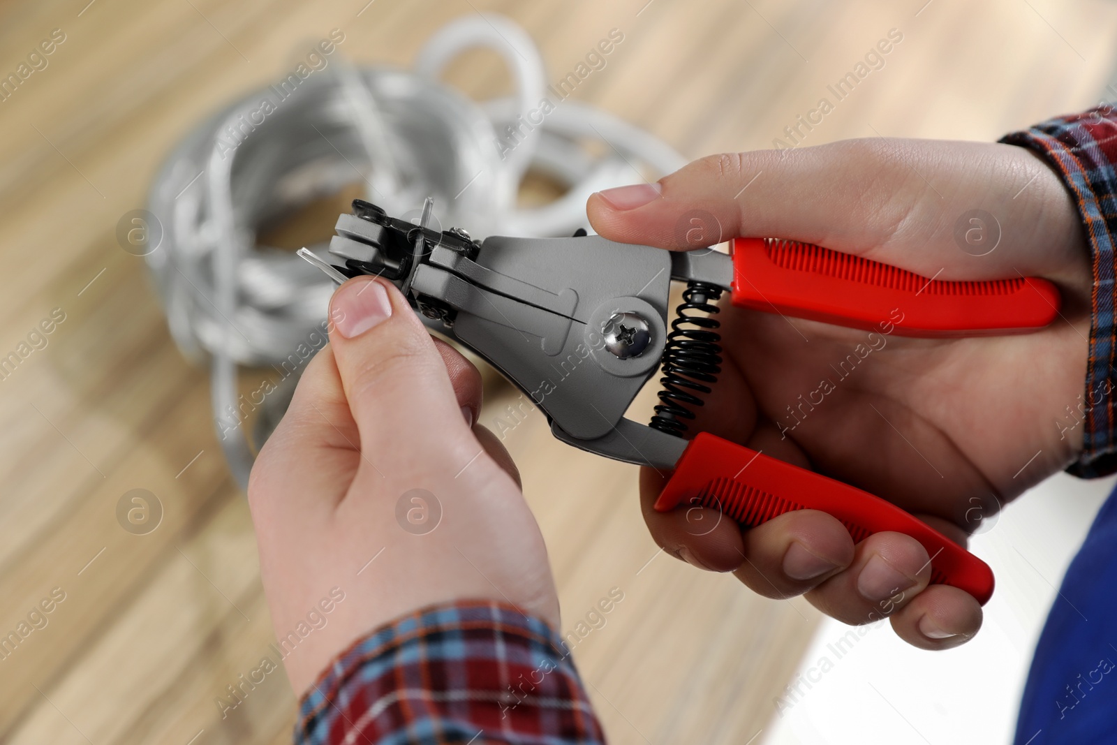 Photo of Professional electrician stripping wiring at wooden table, above view