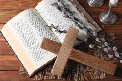 Photo of Cross, Bible and willow branches on wooden table, flat lay