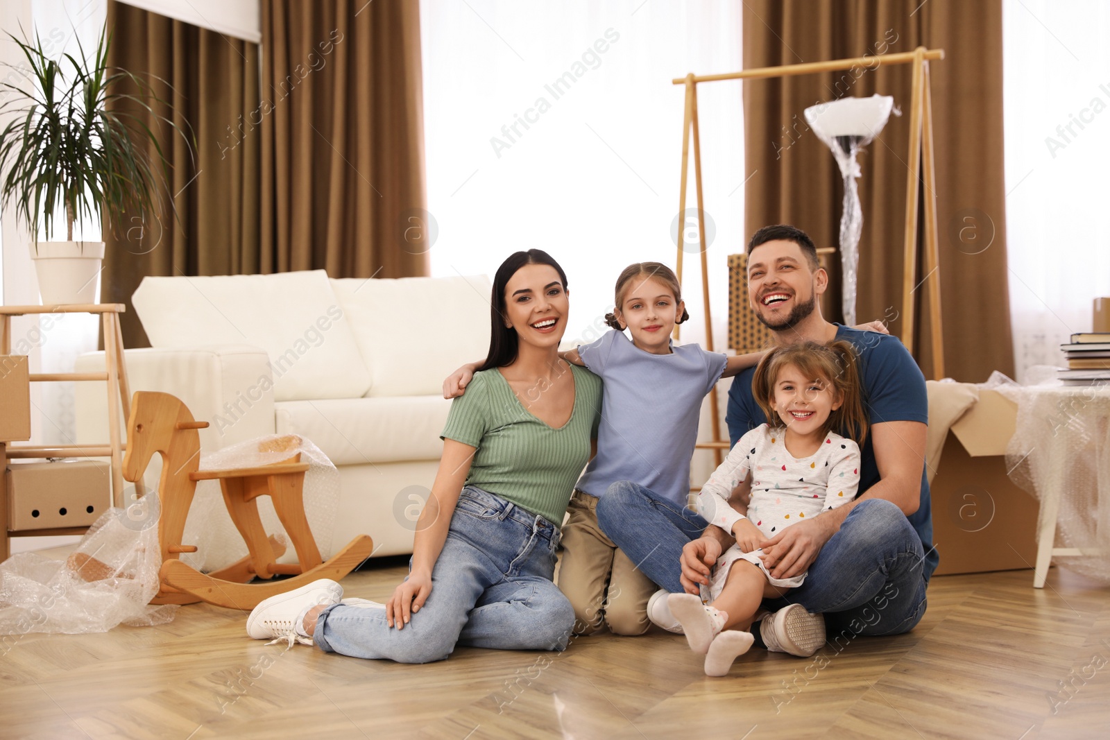 Photo of Portrait of happy family sitting on floor in new house. Moving day