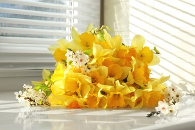 Yellow daffodils and beautiful white flowers of plum tree on windowsill