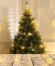 Image of Empty wooden surface and blurred view of Christmas tree in room, space for text. Interior design