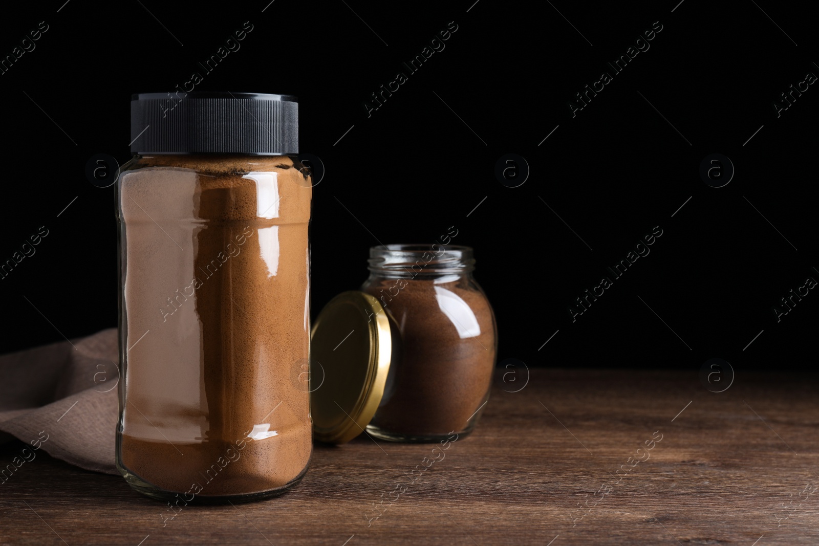 Photo of Jars of instant coffee on wooden table. Space for text