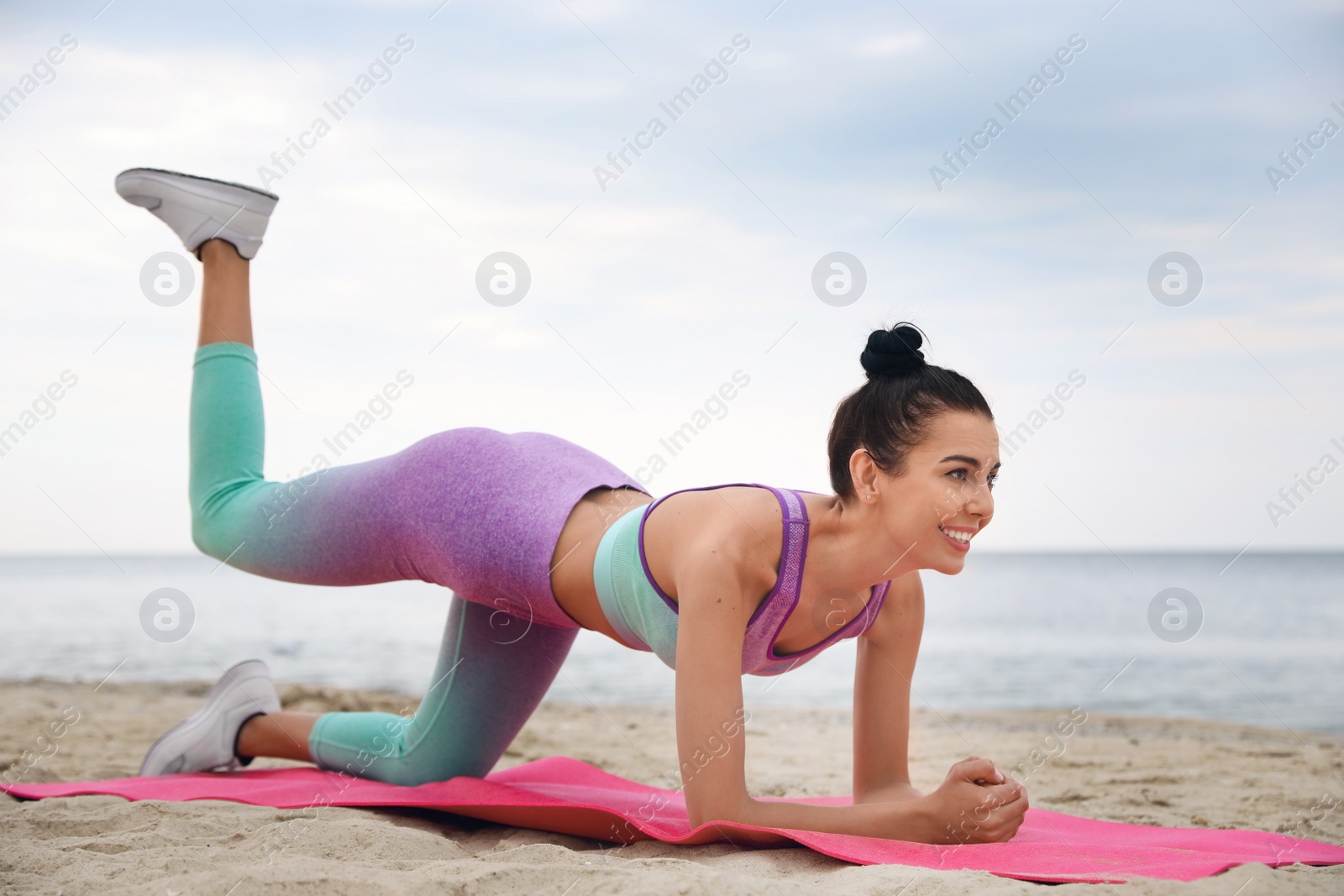 Photo of Young woman doing exercise on beach. Body training