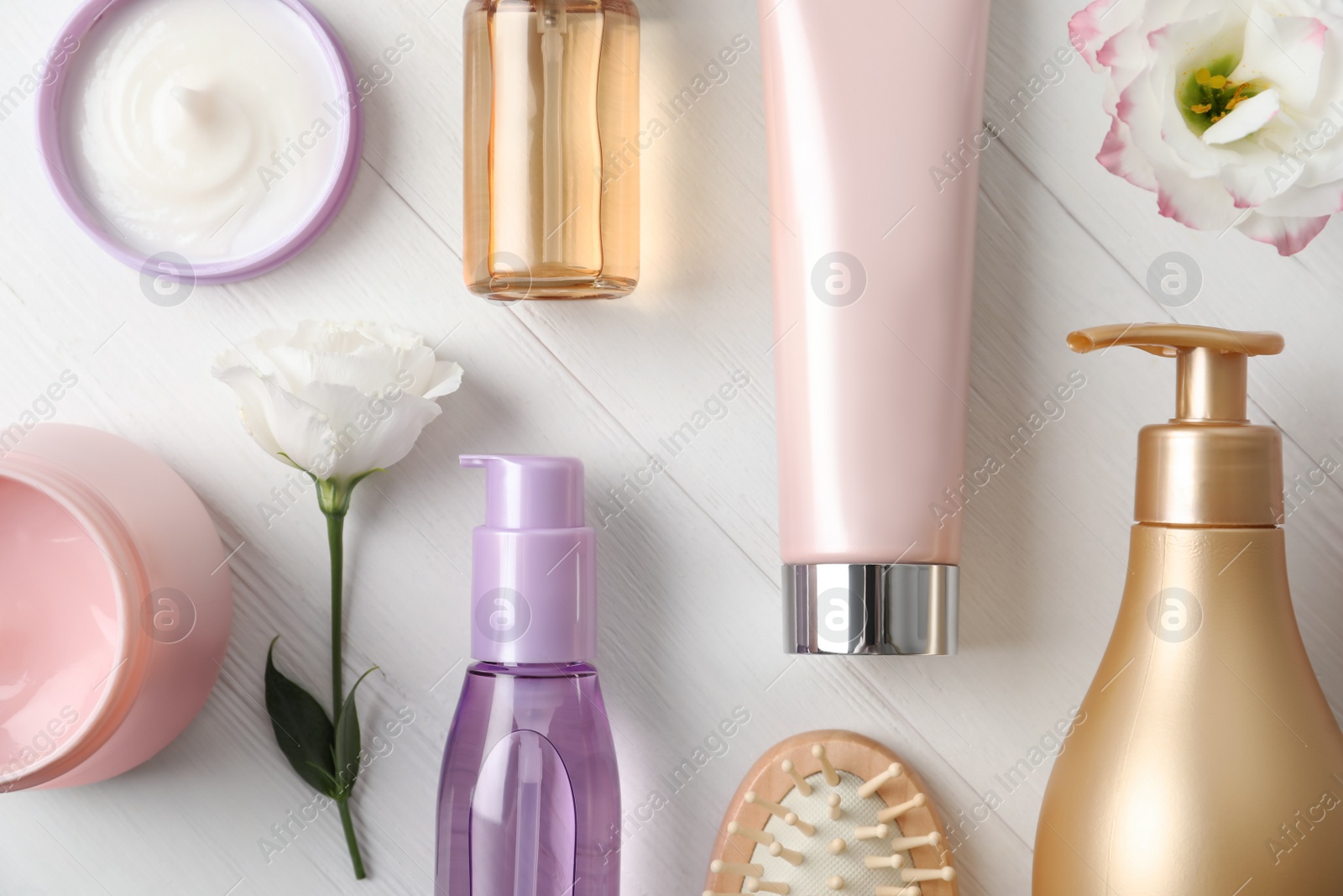 Photo of Flat lay composition with different hair products and flowers on white wooden table