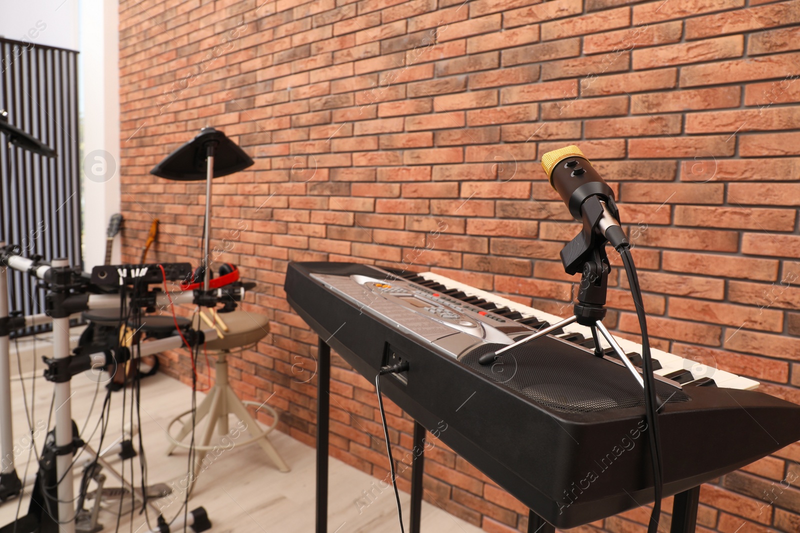 Photo of Musical instruments near red brick wall indoors, focus on synthesizer