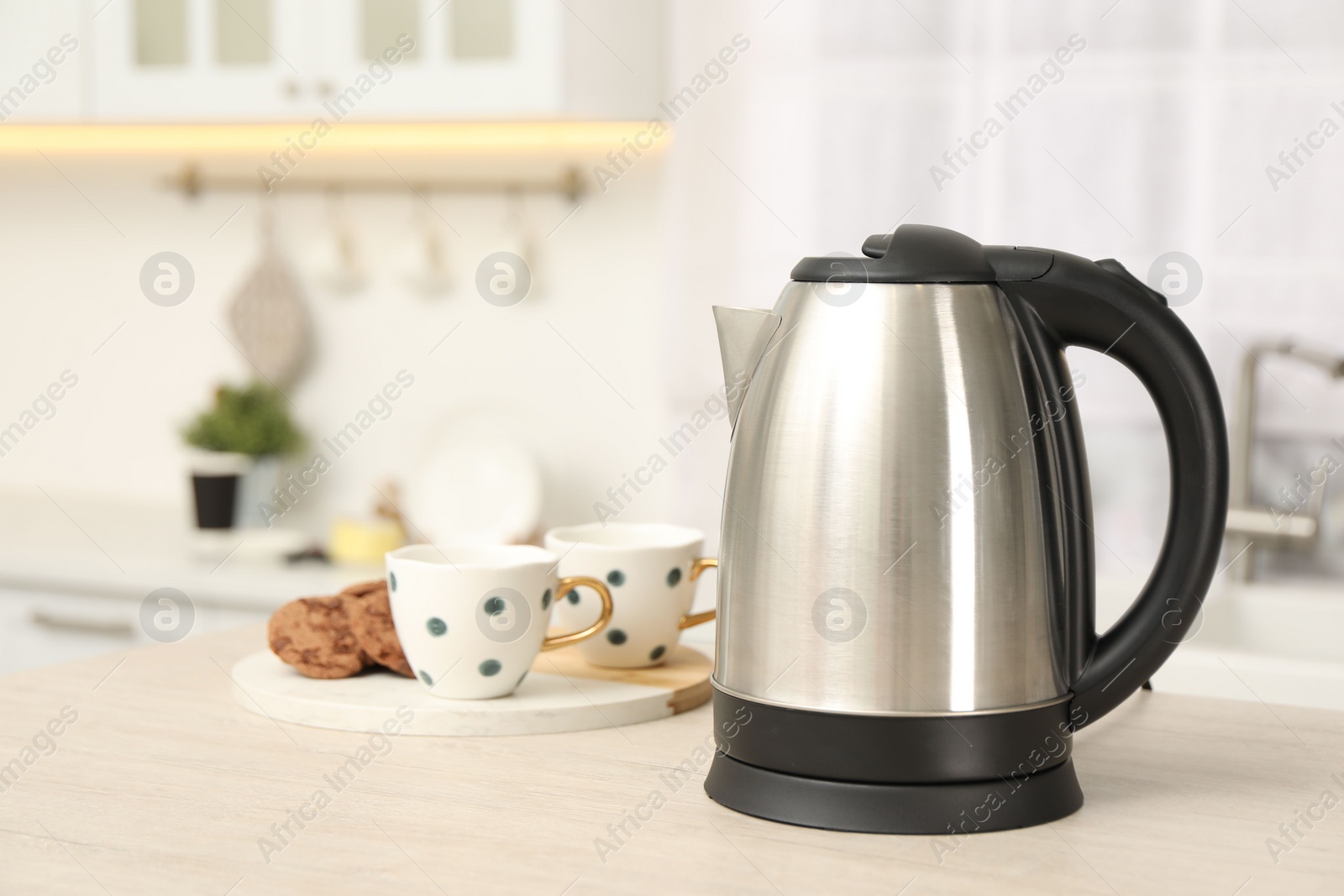 Photo of Modern electric kettle on table in kitchen. Space for text