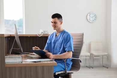 Photo of Smiling medical assistant working at hospital reception. Space for text