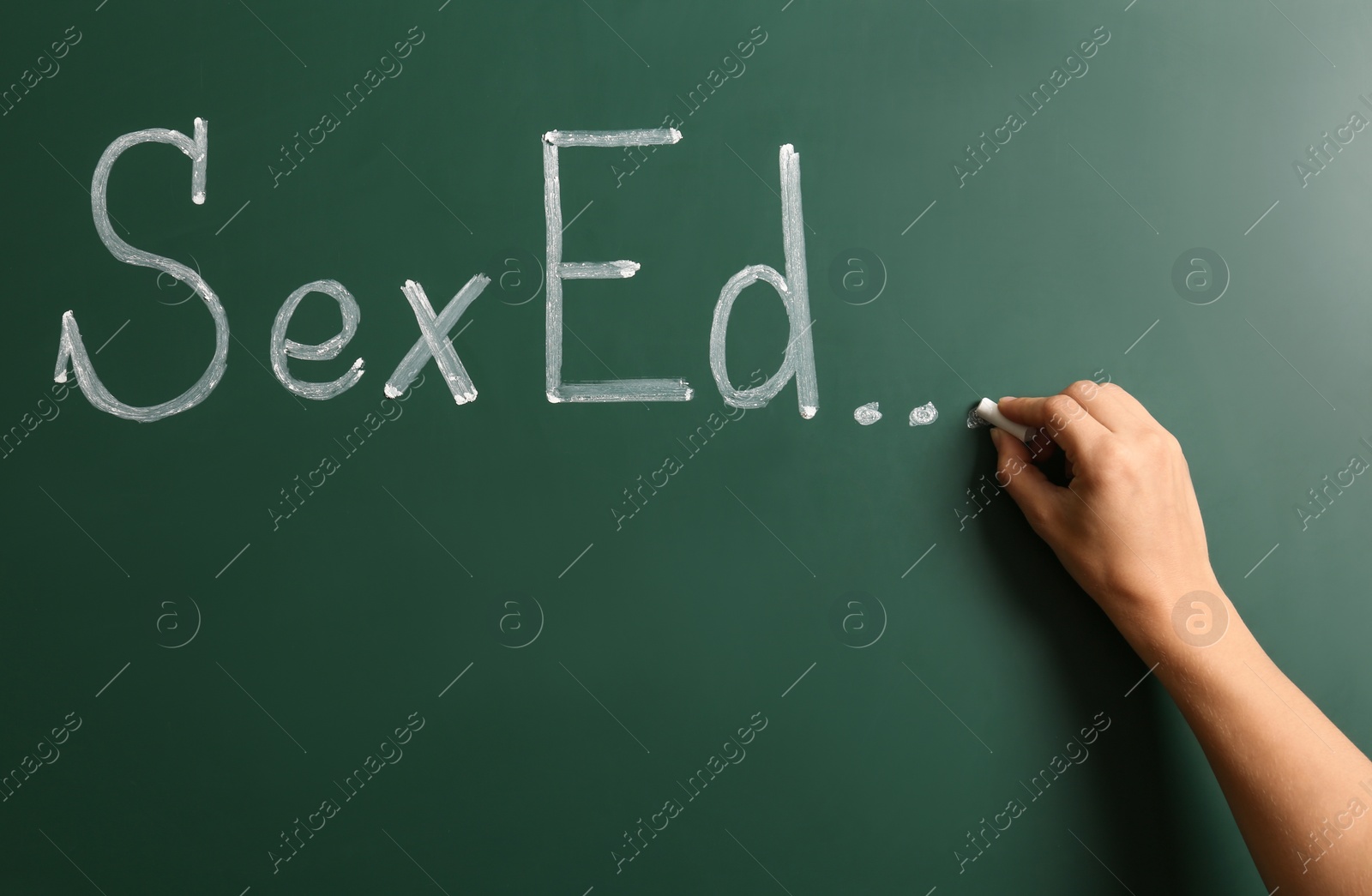 Photo of Woman writing text "SEX ED..." on green chalkboard