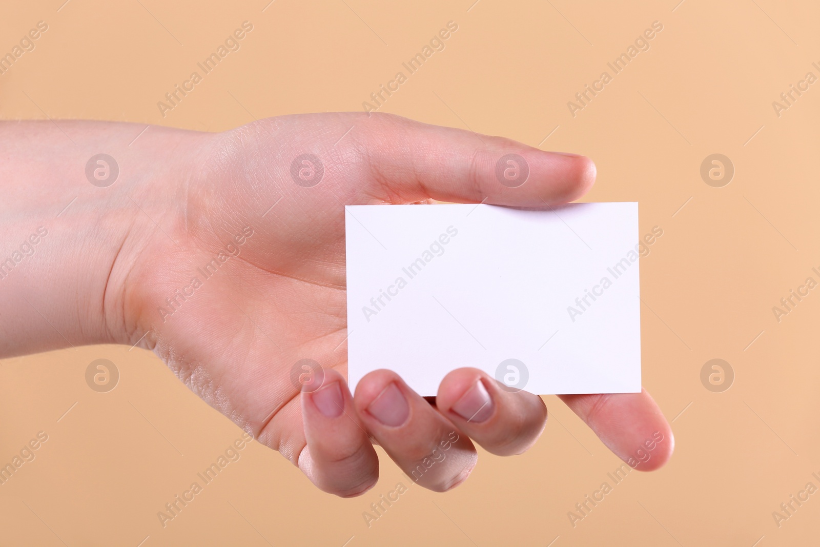 Photo of Man holding paper card on pale orange background, closeup. Mockup for design