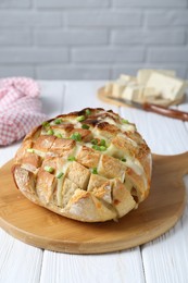 Photo of Freshly baked bread with tofu cheese and green onions on white wooden table