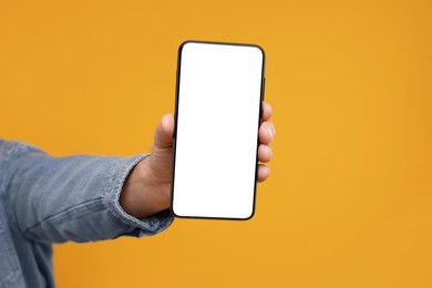 Man showing smartphone on orange background, closeup. Mockup for design