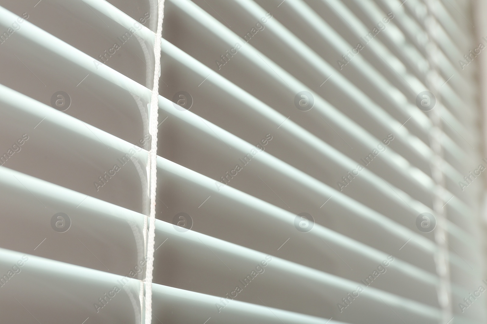 Photo of Closed modern white window blinds, closeup view