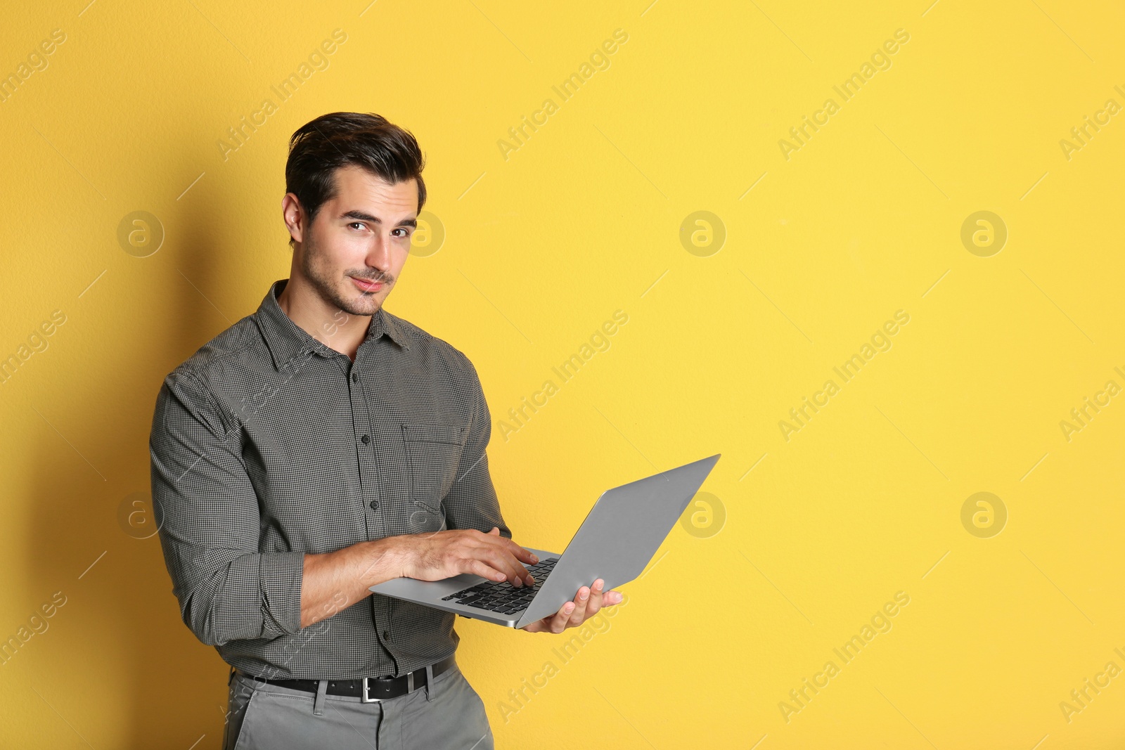 Photo of Young male teacher with laptop on yellow background. Space for text