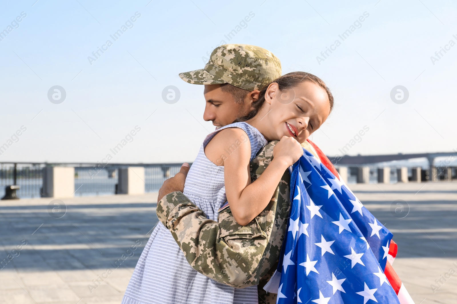 Photo of Soldier with flag of USA and his little daughter hugging outdoors, space for text