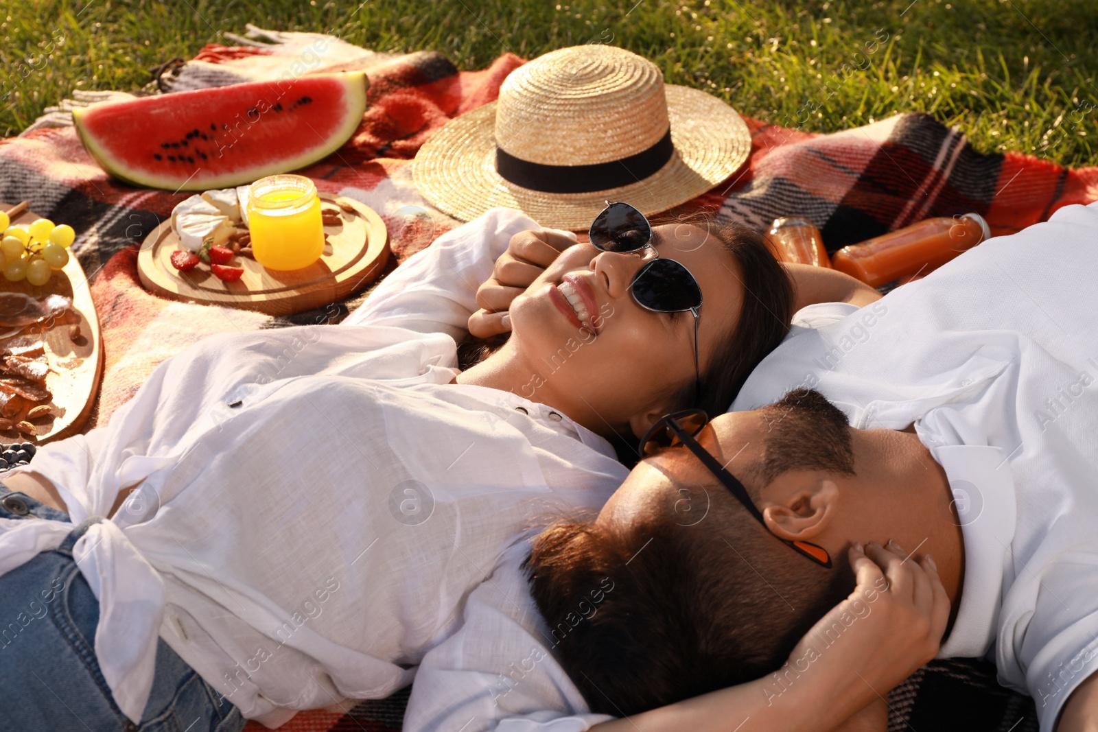 Photo of Happy young couple resting on picnic plaid outdoors