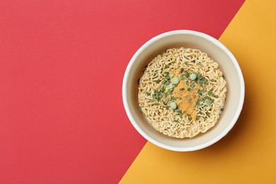 Cup of instant noodles on color background, top view. Space for text