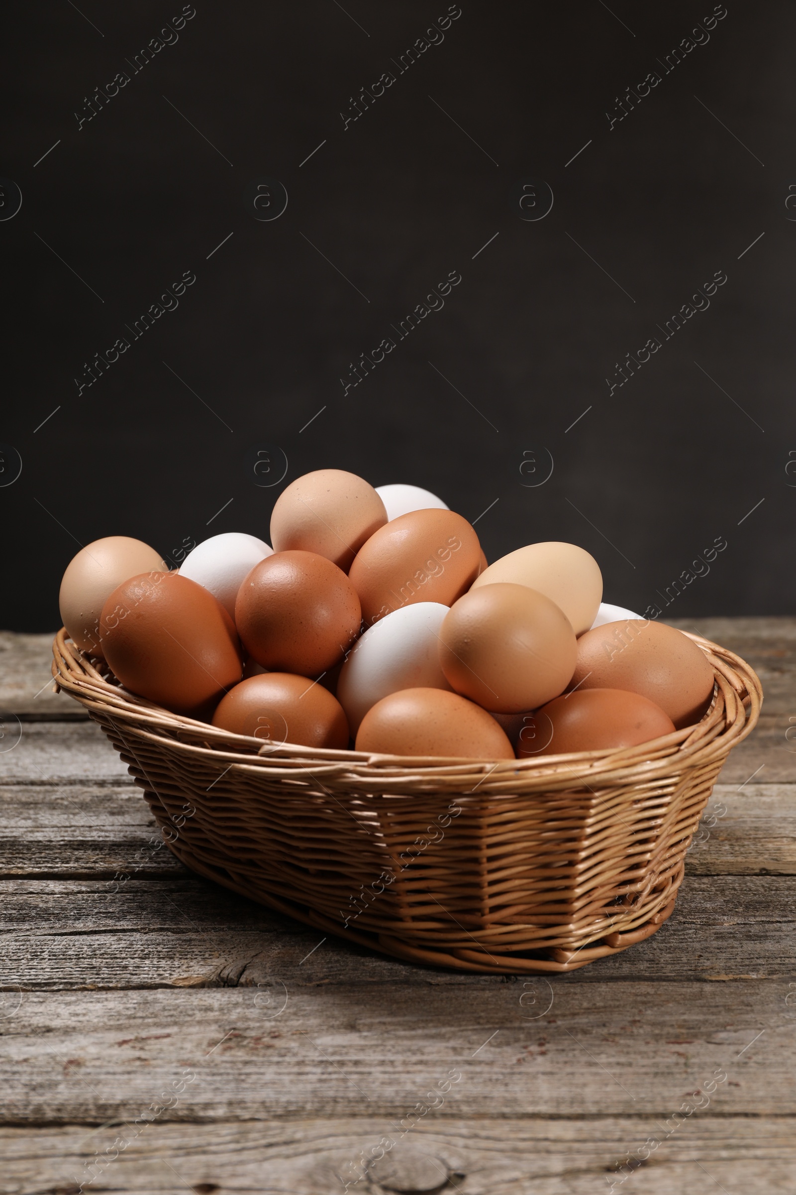 Photo of Fresh chicken eggs in wicker basket on wooden table