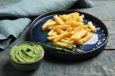 Photo of Plate with delicious french fries, avocado dip and rosemary served on grey wooden table