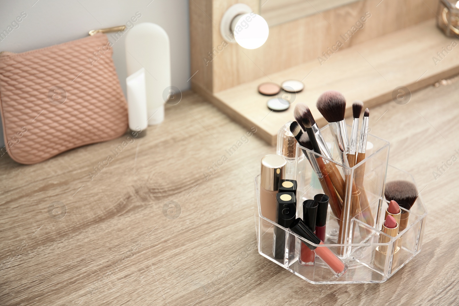 Photo of Makeup cosmetic products and tools in organizer on dressing table