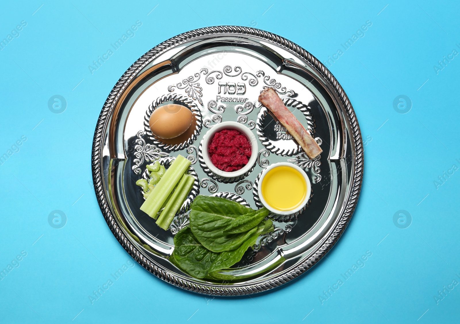 Photo of Passover Seder plate (keara) with symbolic meal on light blue background, top view. Pesah celebration