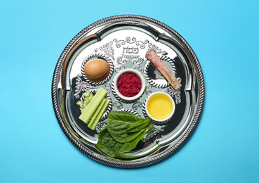 Passover Seder plate (keara) with symbolic meal on light blue background, top view. Pesah celebration