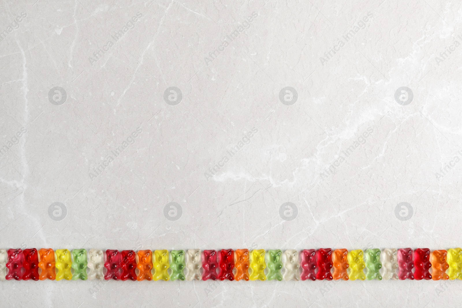 Photo of Flat lay composition with colorful gummy bears on grey background. Space for text