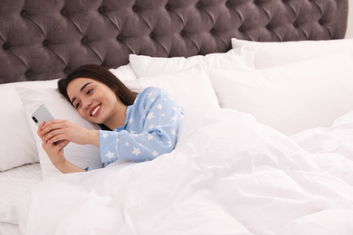 Photo of Young woman addicted to smartphone in bed at home