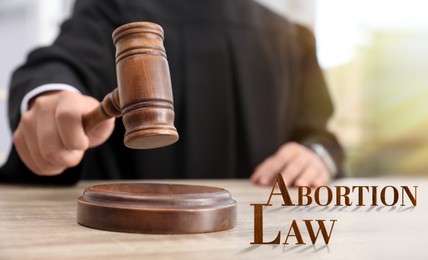 Image of Abortion law. Judge with gavel at wooden table, closeup