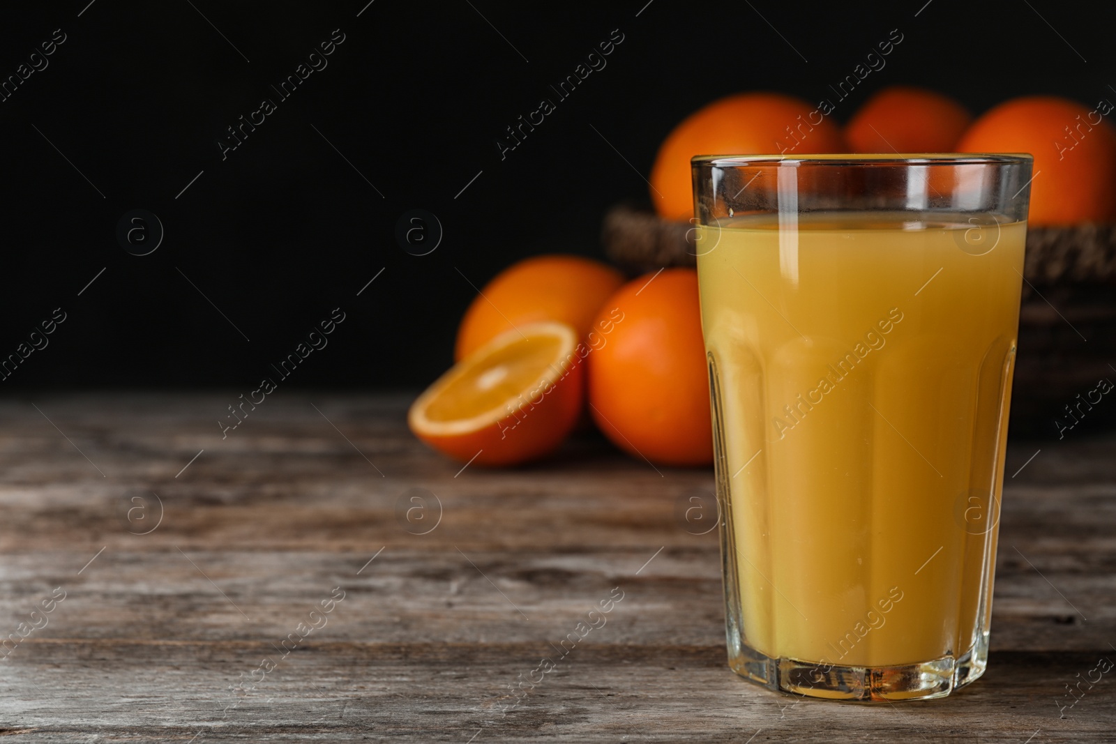 Photo of Glass of orange juice on wooden table. Space for text