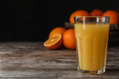 Photo of Glass of orange juice on wooden table. Space for text