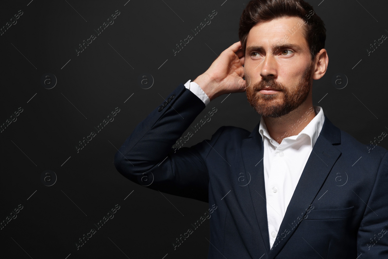 Photo of Portrait of handsome bearded man looking away on black background. Space for text