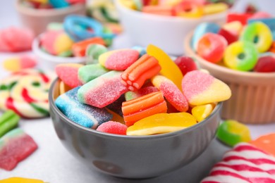 Photo of Bowl of tasty colorful jelly candies on white table, closeup