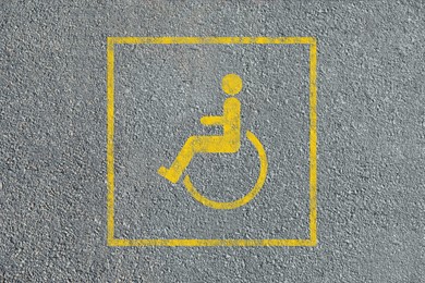 Image of Wheelchair symbol on asphalt road, top view. Disabled parking permit