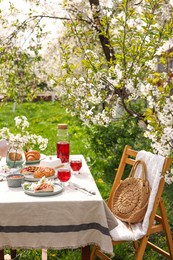 Photo of Stylish table setting with beautiful spring flowers, fruit drink and pie in garden