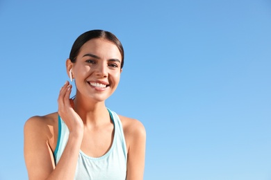 Photo of Young sportswoman with wireless earphones outdoors