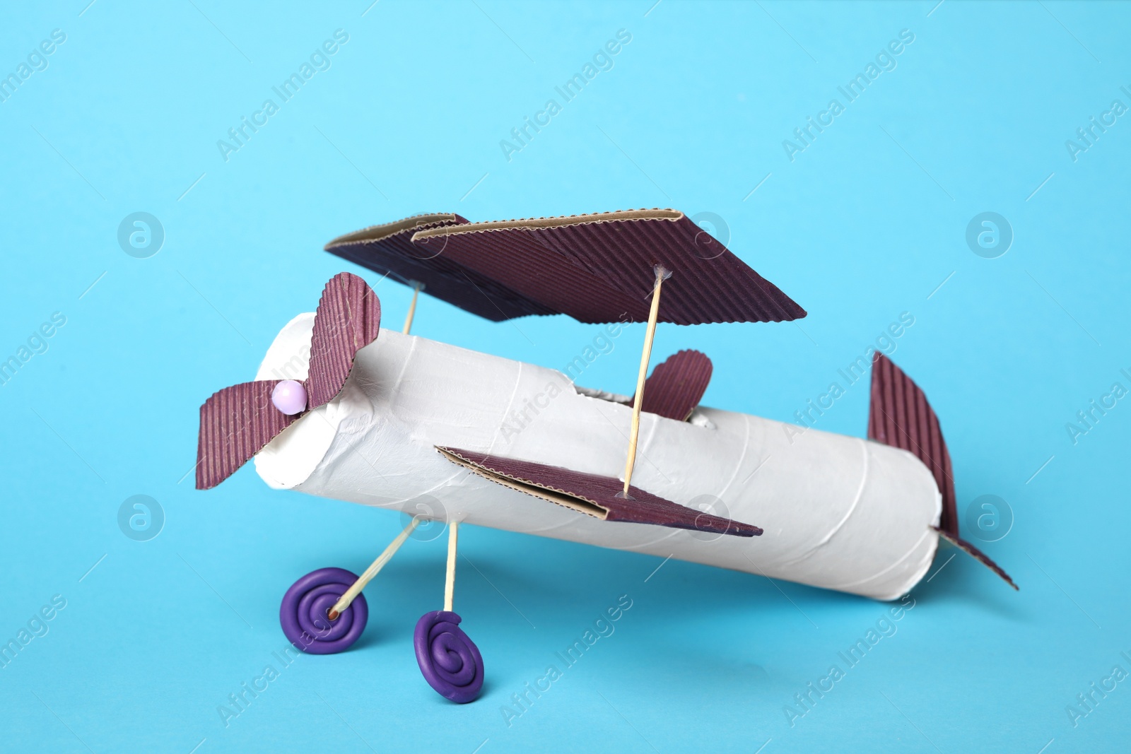 Photo of Toy plane made of toilet paper hub on light blue background