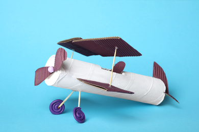 Toy plane made of toilet paper hub on light blue background