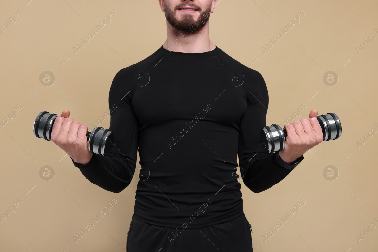 Photo of Man with exercising dumbbells on brown background, closeup