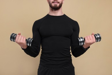 Man with exercising dumbbells on brown background, closeup