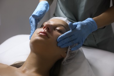 Photo of Young woman receiving facial massage in salon