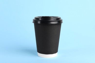 Photo of Black paper cup with plastic lid on light blue background. Coffee to go