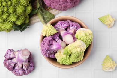 Photo of Various cauliflower cabbages on white tiled table, flat lay