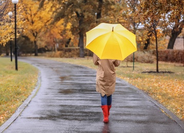 Photo of Woman with umbrella taking walk in autumn park on rainy day