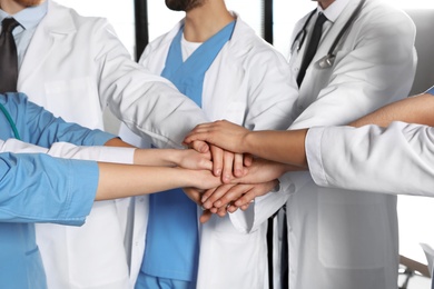 Photo of Team of medical workers holding hands together, closeup. Unity concept
