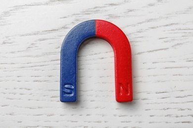 Photo of Red and blue horseshoe magnet on wooden background, top view